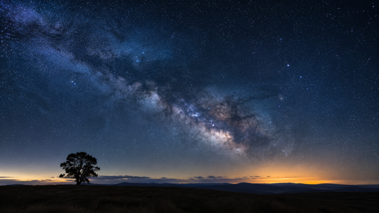 A vast star-filled night sky and the Milky Way arcing over a dark landscape, illustrating creation pointing to the existence of God.