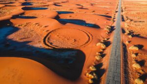 Aerial view of red desert dunes where a trail loops in a circle back on itself beside one straight road running to the horizon, for an article on Psalm 119